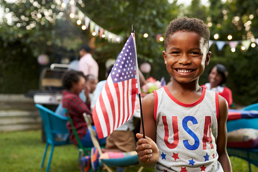 Young black boy holding flag at 4th July family garden party