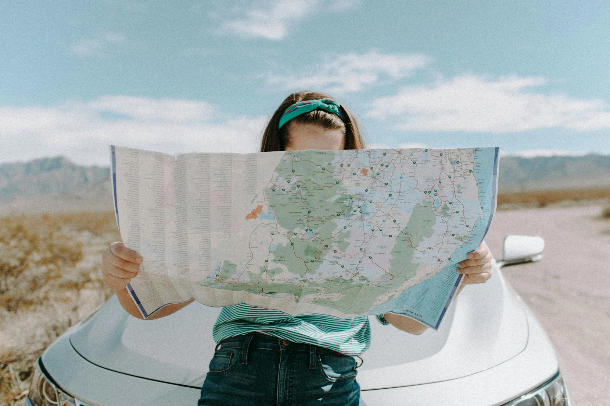 Map-of-US Young woman holds up a paper map, which covers her face