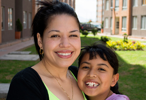 A woman and her young child smile at the camera
