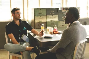 Two men sit at a table having a discussion.