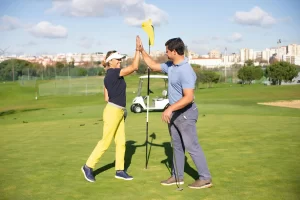 Two people high five while standing on a golf course