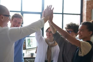 Five people stand next to a window and high-five.