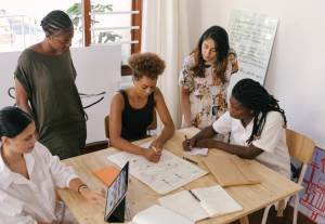 Five women sitting around a wooden table training on ethical considerations. 