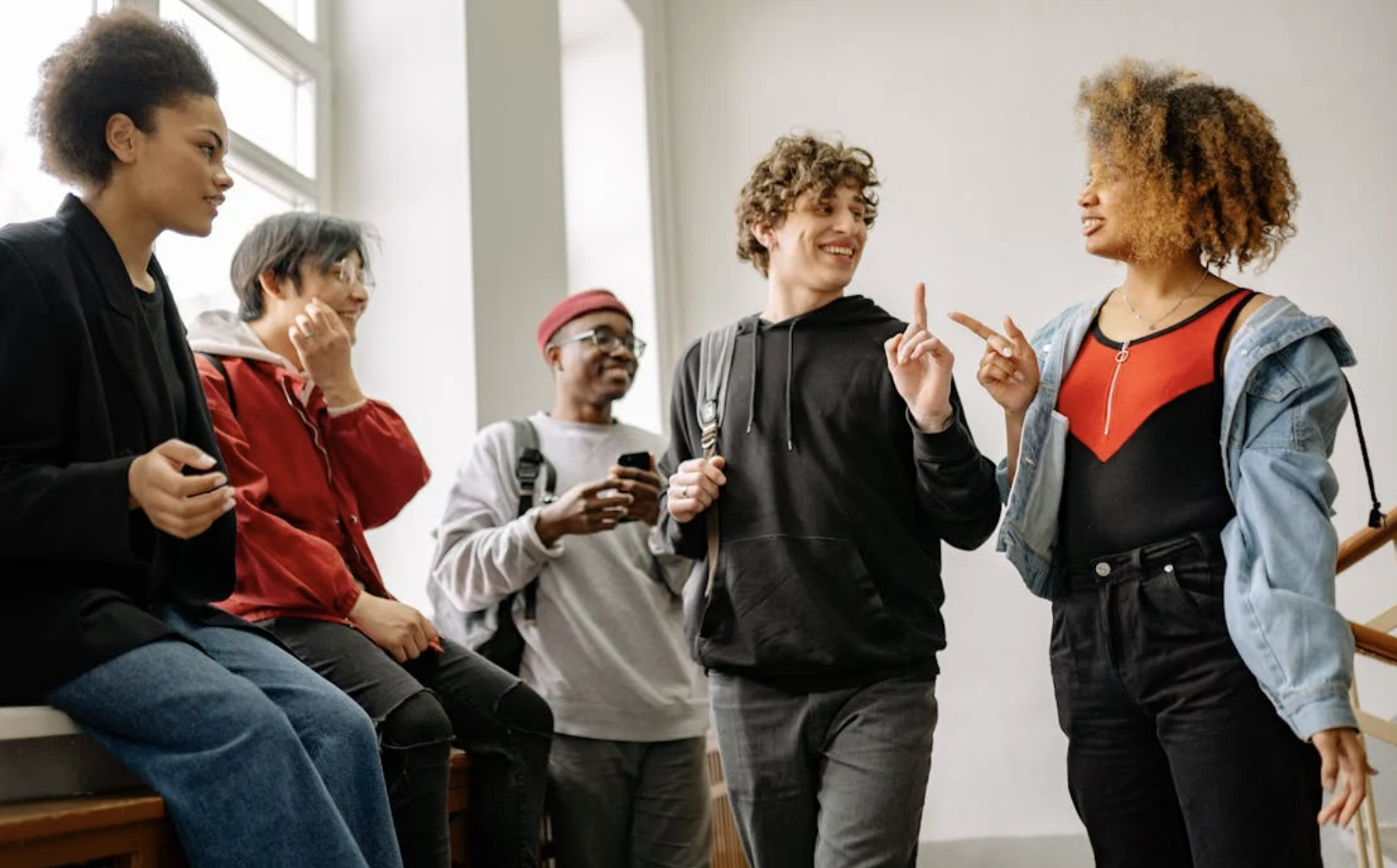 A group of classmates talking to each other in the hallway.