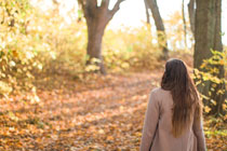 Woman stands with her back to the camera looking at a fall woods scene