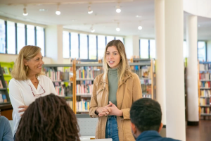 Woman stands in library and talks to group of people