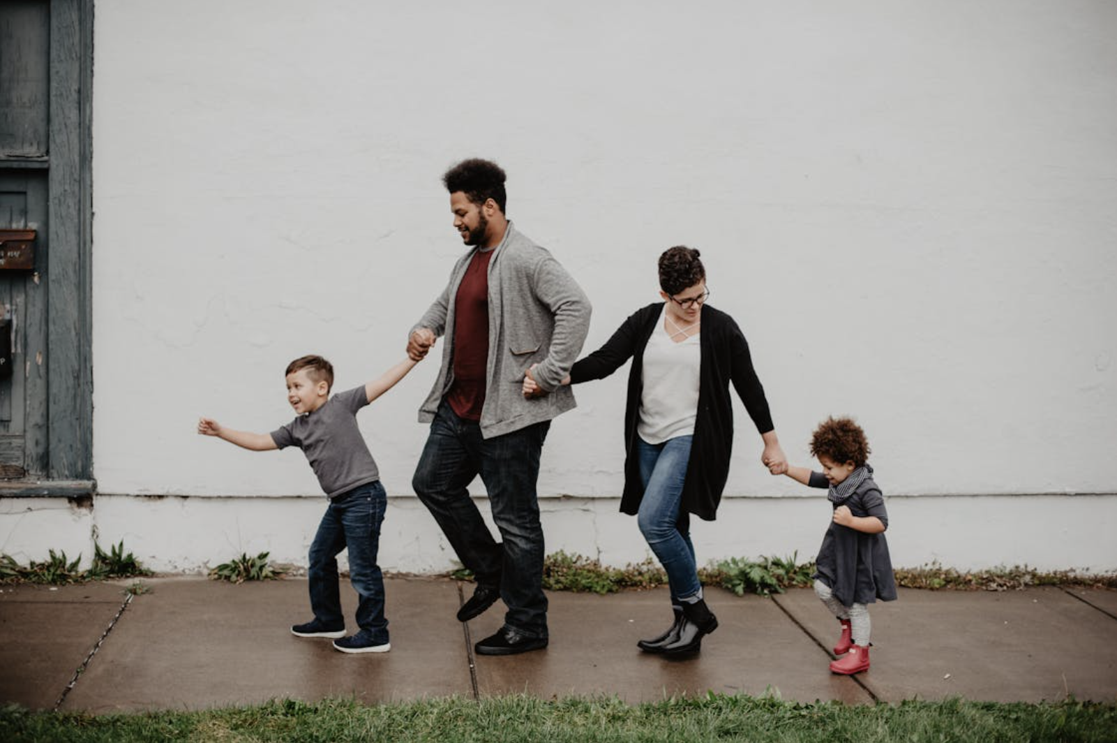 A family holding hands walking around their neighborhood.