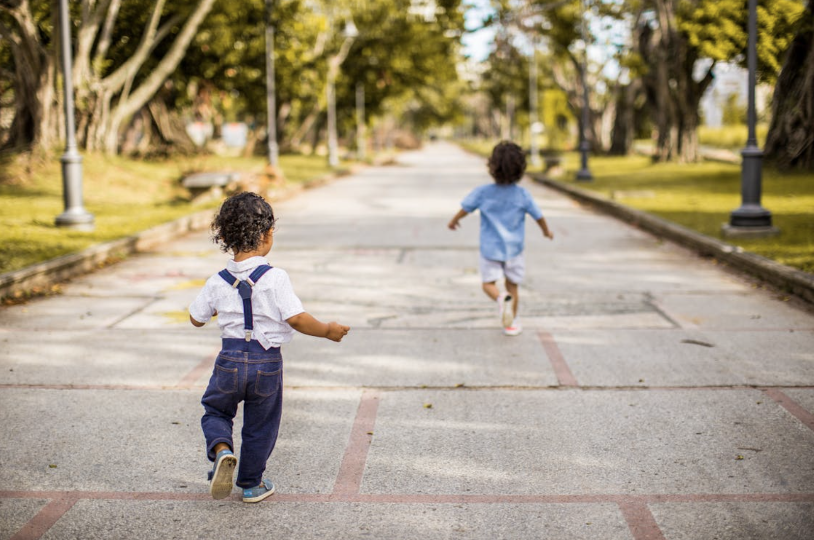 Two toddlers running around in park.