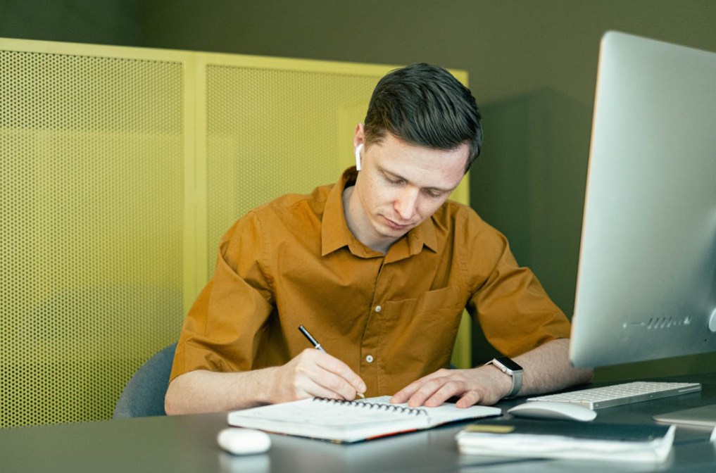 A man reading and taking notes on a report.