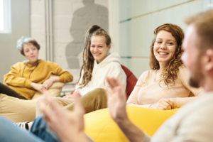 Four people sit comfortably in bean bag chairs and smile and talk