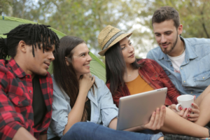 Four youg adults look at a tablet and smile at each other