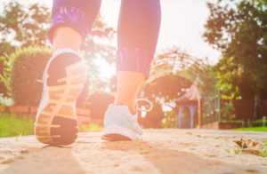  Close-up of shoes of person walking on sidewalk with sun behind them