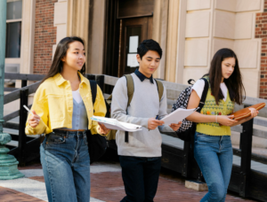 Three students walking together next to a building on college campus