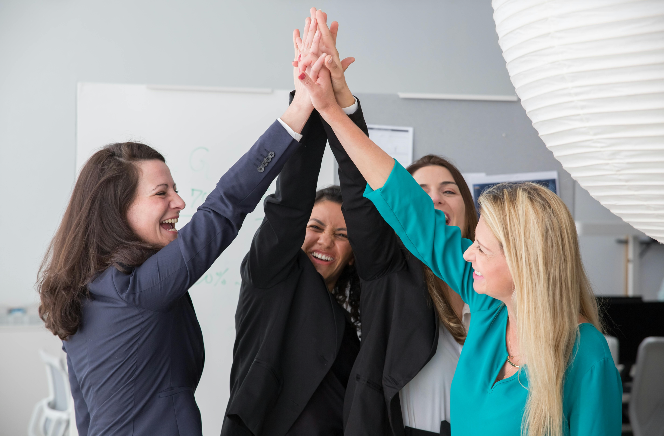 Four people high five in an office setting