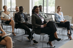 Several people sit in chairs at a conference