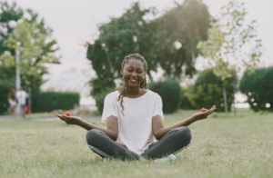 Woman sitting on grass smiling while meditating