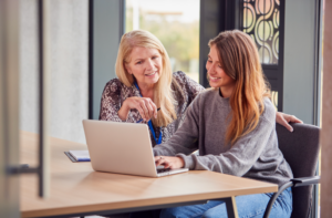 College staff person helps a student on laptop
