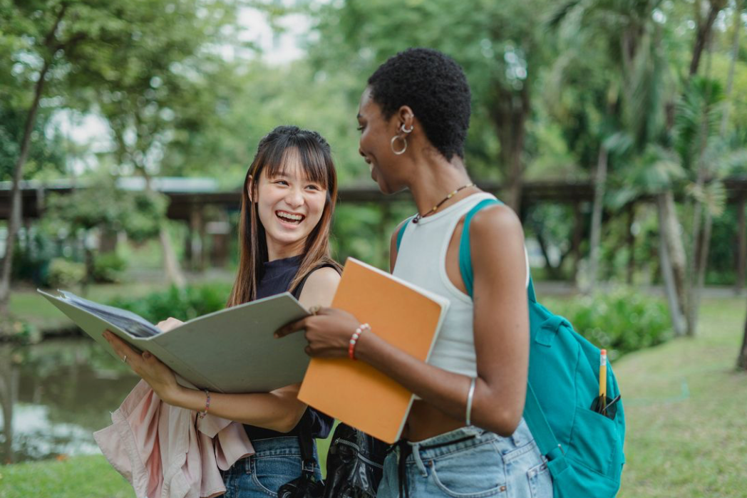 Two students laughing and studying together outdoors