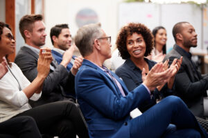A crowd claps and smiles at a conference