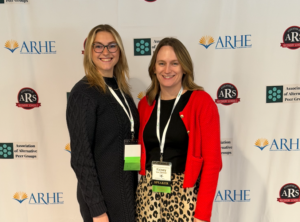 Carly and Kelsey pose in front of a backdrop at ARHE conference