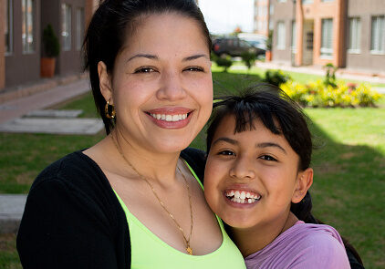 A mother with her daughter laughing outdoor.